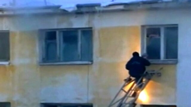 Zalegający śnieg, spada na strażaka idącego po drabinie